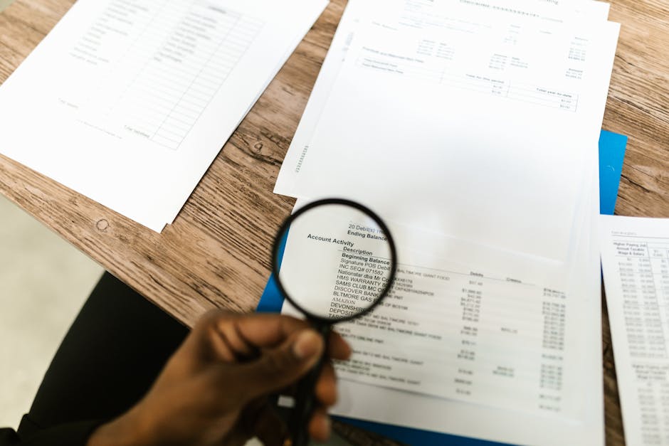 A hand using a magnifying glass to review property documents